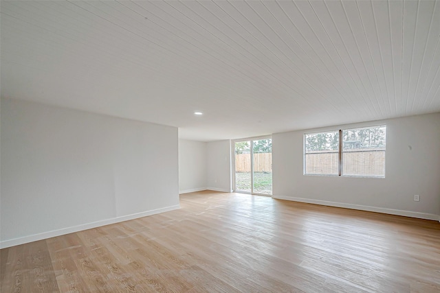 empty room featuring wood ceiling, plenty of natural light, and light wood-type flooring