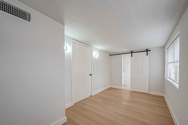 interior space with a barn door, wood ceiling, and light hardwood / wood-style flooring