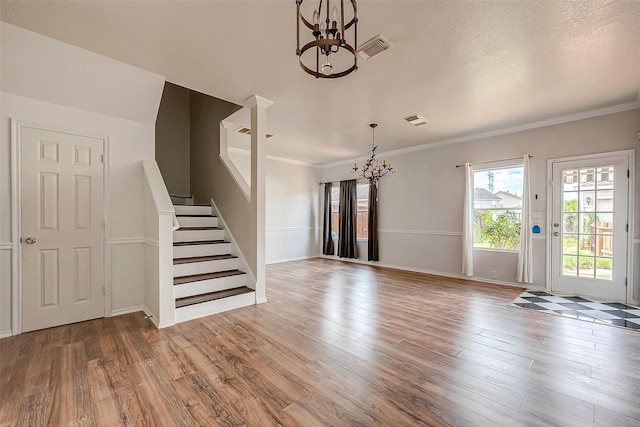 interior space featuring wood-type flooring, crown molding, a textured ceiling, and a chandelier