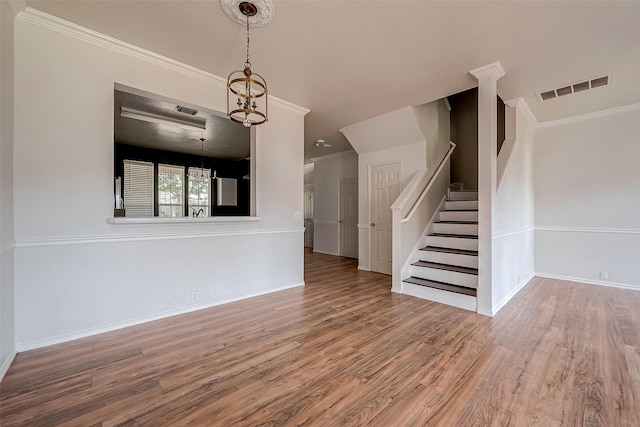 unfurnished living room with hardwood / wood-style flooring, ornamental molding, and a chandelier