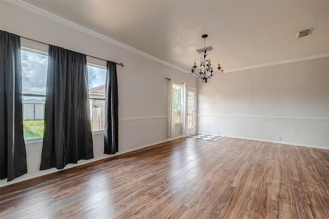 unfurnished room with crown molding, hardwood / wood-style floors, and a chandelier