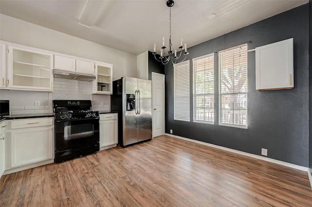 kitchen featuring black gas range oven, pendant lighting, white cabinets, stainless steel fridge, and light hardwood / wood-style flooring