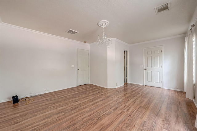 unfurnished room with crown molding, hardwood / wood-style floors, and a chandelier