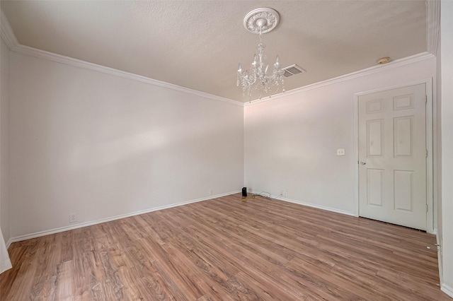 spare room featuring wood-type flooring, crown molding, a textured ceiling, and an inviting chandelier