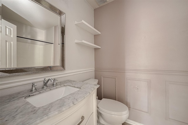 bathroom with vanity, toilet, and a shower