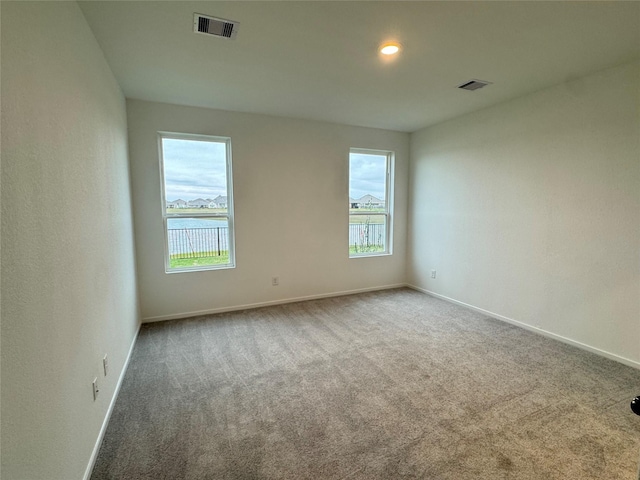 unfurnished room featuring carpet floors, a healthy amount of sunlight, and a water view