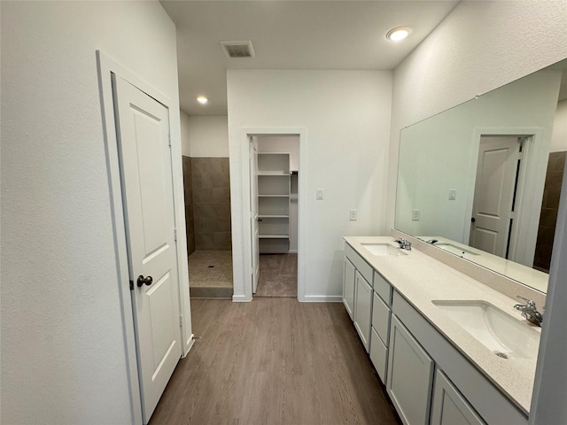 bathroom featuring a tile shower, vanity, and hardwood / wood-style flooring