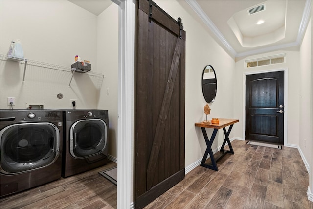 clothes washing area with a barn door, ornamental molding, separate washer and dryer, and dark wood-type flooring