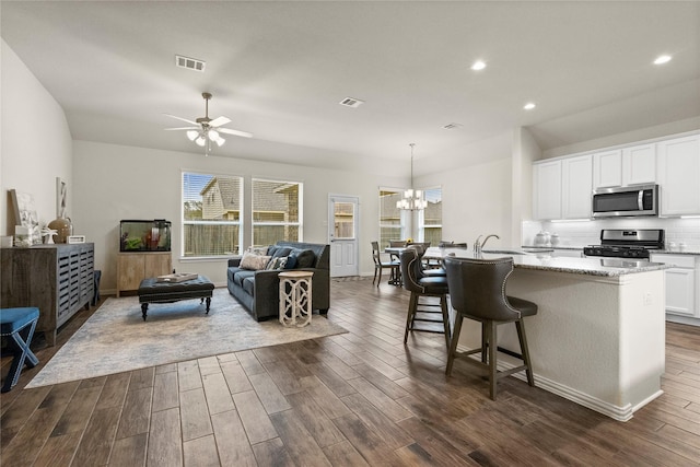 kitchen with stainless steel appliances, white cabinetry, dark wood-type flooring, and decorative light fixtures