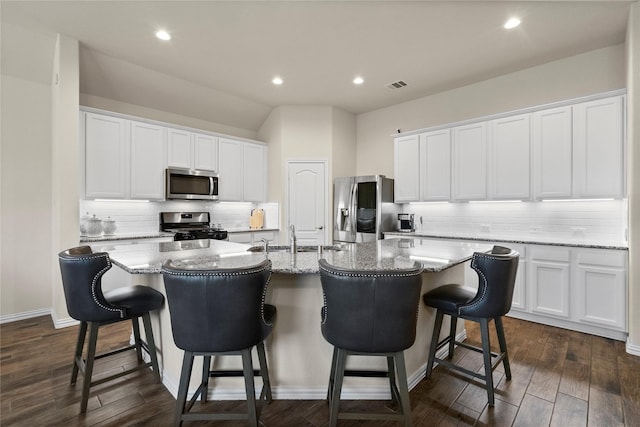 kitchen with stainless steel appliances, a kitchen breakfast bar, a center island with sink, and white cabinets