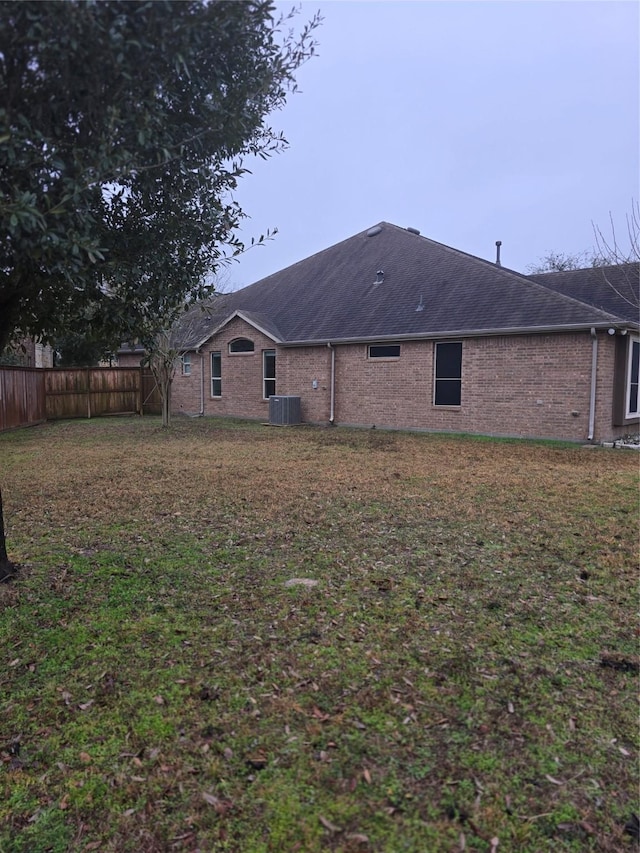 rear view of property featuring a yard and central air condition unit