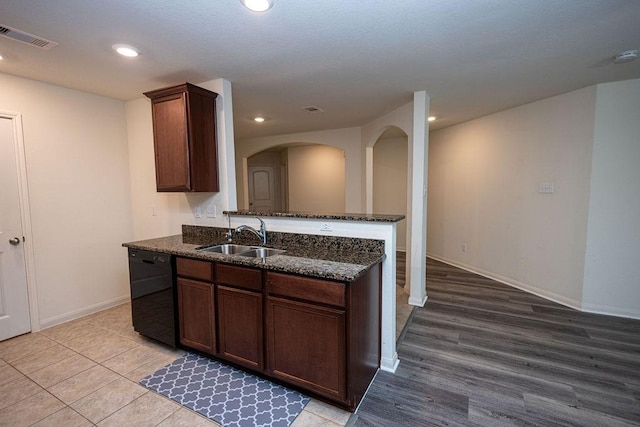 kitchen with sink, dark stone countertops, dishwasher, kitchen peninsula, and light hardwood / wood-style floors