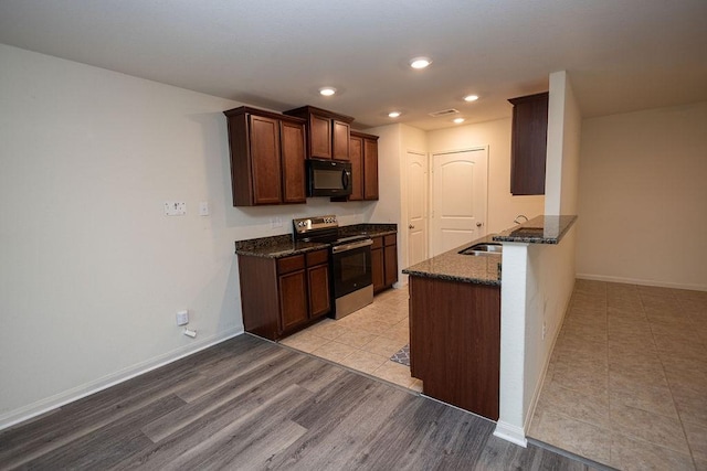 kitchen with stainless steel electric stove, sink, dark stone countertops, kitchen peninsula, and light hardwood / wood-style flooring