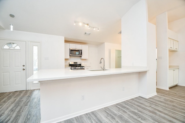 kitchen featuring sink, white cabinets, kitchen peninsula, stainless steel appliances, and light wood-type flooring