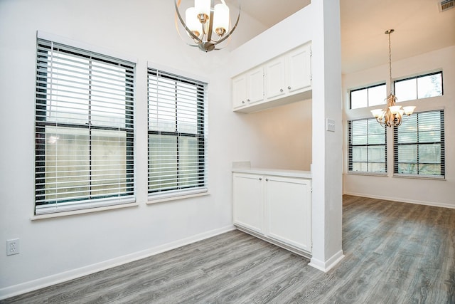 unfurnished dining area featuring a towering ceiling, a notable chandelier, and light wood-type flooring