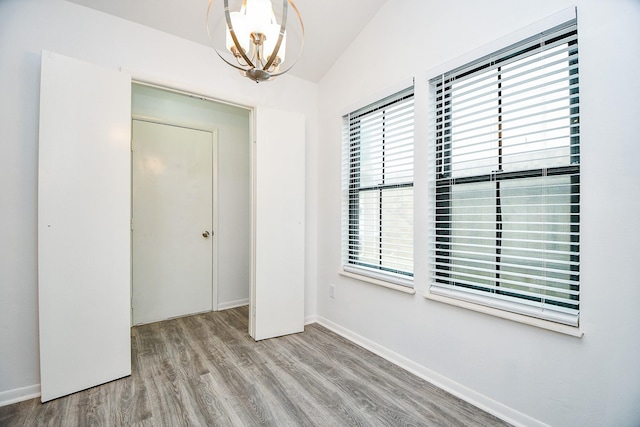 interior space featuring a chandelier, light hardwood / wood-style floors, vaulted ceiling, and a closet