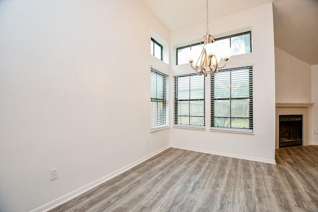 unfurnished dining area featuring an inviting chandelier and hardwood / wood-style flooring