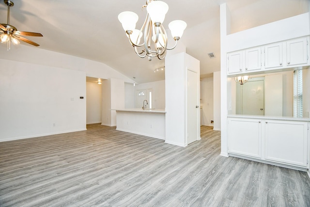 unfurnished living room featuring sink, ceiling fan with notable chandelier, vaulted ceiling, and light hardwood / wood-style floors