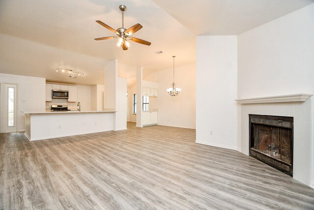 unfurnished living room with lofted ceiling, sink, ceiling fan with notable chandelier, and light wood-type flooring