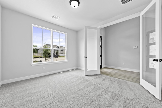 empty room with baseboards, carpet floors, visible vents, and french doors