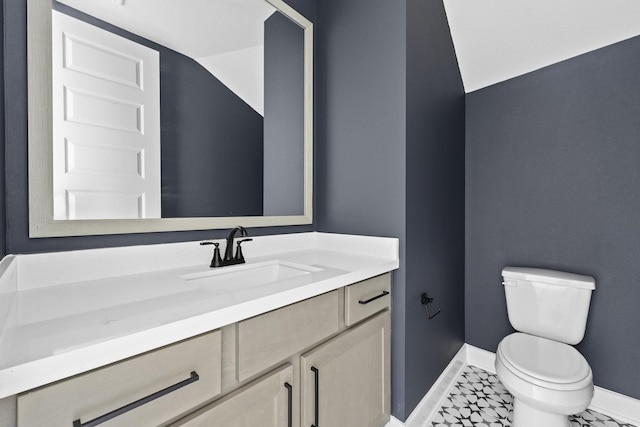 half bathroom featuring toilet, vanity, and baseboards