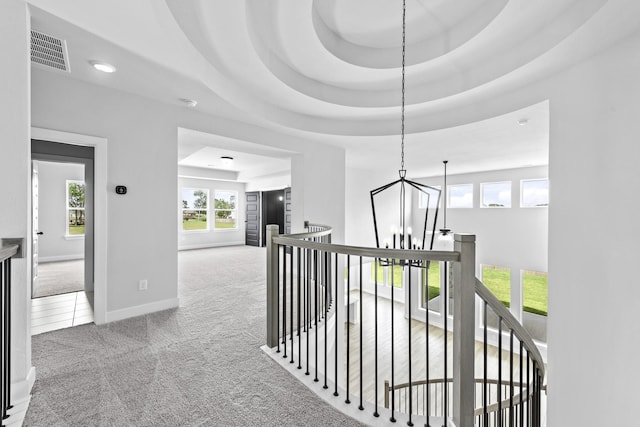 hall featuring carpet floors, an upstairs landing, a notable chandelier, and visible vents