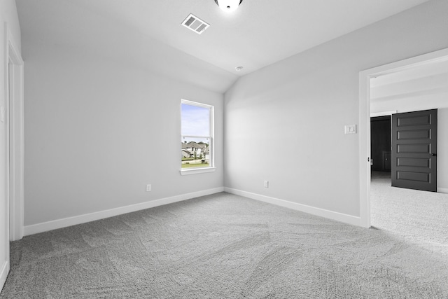 carpeted spare room with baseboards, visible vents, and lofted ceiling