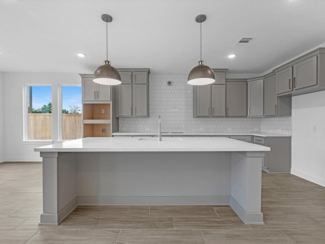 32602 Fly Fish Way, Fulshear, TX 77441 - kitchen with gray cabinetry, a large island with sink, backsplash, light wood-style flooring, and recessed lighting