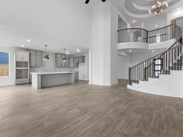 32602 Fly Fish Way, Fulshear, TX 77441 - unfurnished living room with recessed lighting, stairs, a high ceiling, light wood-type flooring, and a chandelier