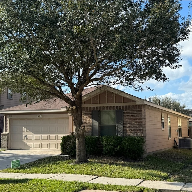 view of front of property with a garage, brick siding, driveway, and central AC