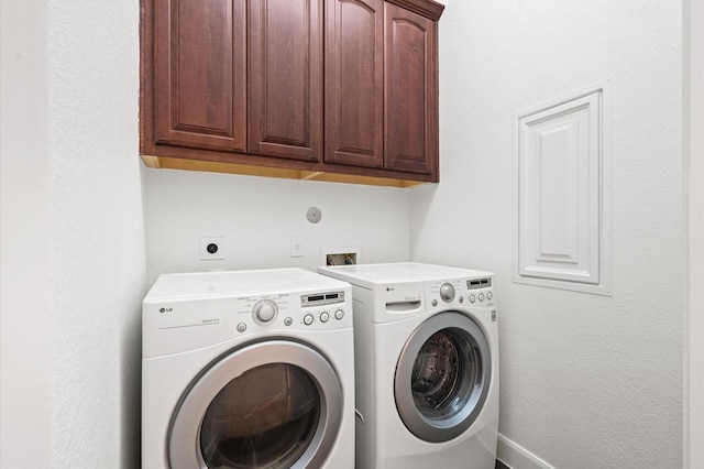 clothes washing area featuring independent washer and dryer and cabinets