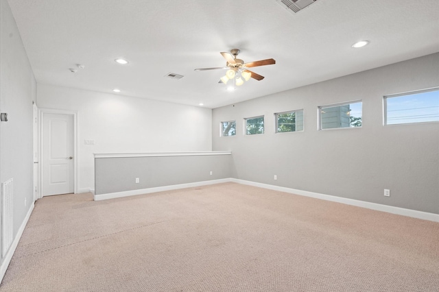 spare room with ceiling fan, light colored carpet, and plenty of natural light