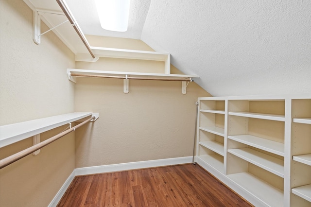 walk in closet with dark hardwood / wood-style flooring and vaulted ceiling