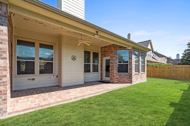 view of exterior entry with a patio area, ceiling fan, and a lawn