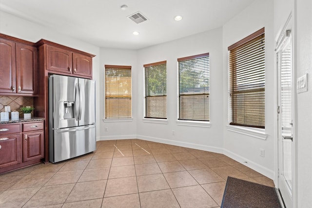 kitchen featuring light tile patterned flooring, stainless steel fridge, and backsplash