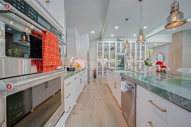 kitchen with white cabinetry, stainless steel appliances, hanging light fixtures, and light hardwood / wood-style flooring