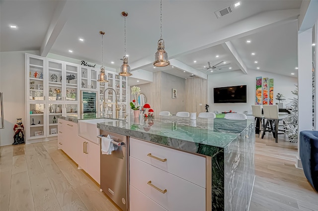 kitchen with decorative light fixtures, lofted ceiling with beams, sink, white cabinets, and a large island