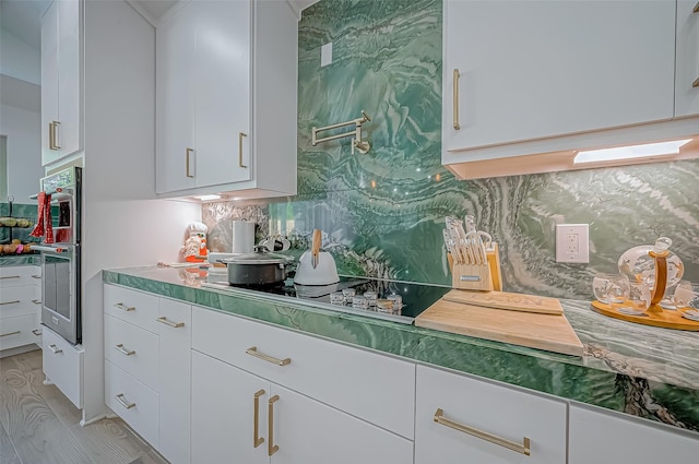 kitchen featuring white cabinetry, tasteful backsplash, and stainless steel double oven