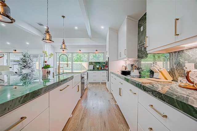 kitchen with pendant lighting, tasteful backsplash, beamed ceiling, white cabinets, and light wood-type flooring