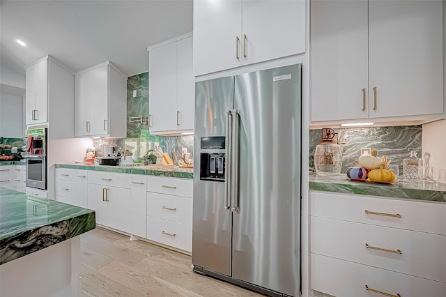 kitchen with stainless steel appliances, white cabinetry, backsplash, and light hardwood / wood-style floors