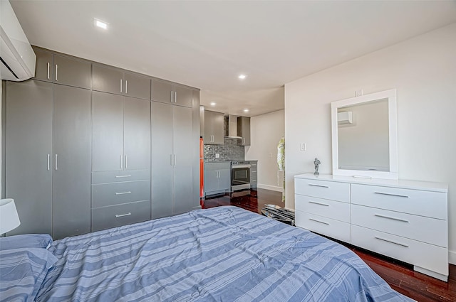 bedroom featuring an AC wall unit, connected bathroom, sink, dark wood-type flooring, and a closet