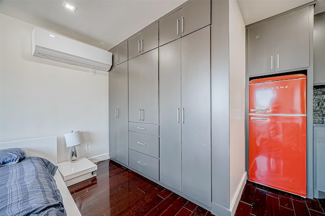 bedroom featuring dark hardwood / wood-style floors, a wall mounted AC, and refrigerator