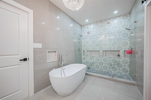 bathroom featuring plus walk in shower, a chandelier, and tile walls