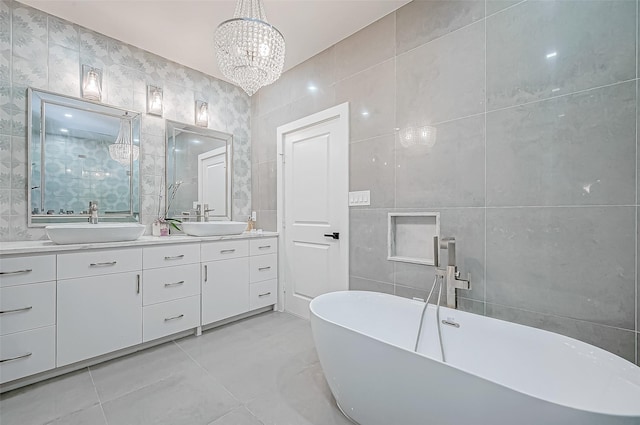 bathroom featuring tile walls, vanity, a notable chandelier, a tub to relax in, and tile patterned floors