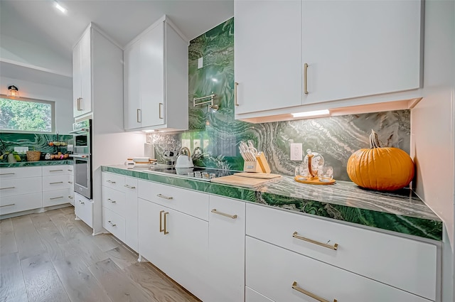 kitchen featuring white cabinetry, double oven, tasteful backsplash, and light wood-type flooring