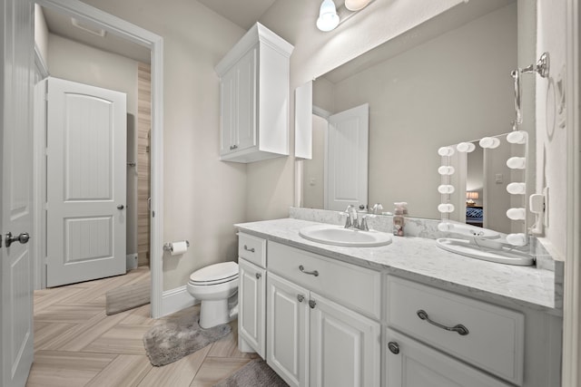 bathroom with vanity, parquet flooring, and toilet