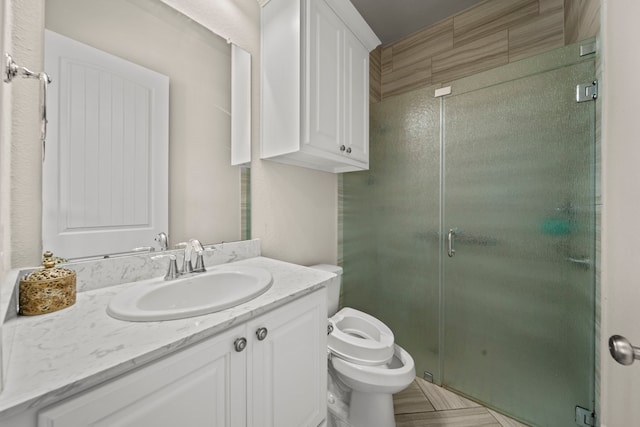 bathroom with vanity, a shower with shower door, and toilet