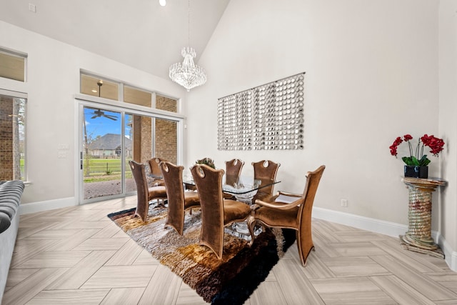 dining area with a towering ceiling, light parquet flooring, and a chandelier