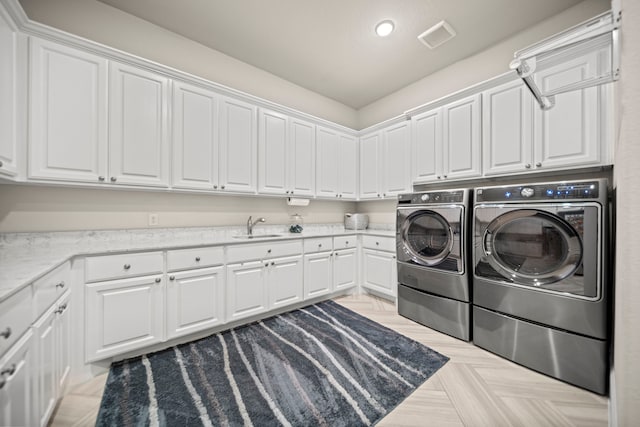 clothes washing area with sink, washer and clothes dryer, and cabinets