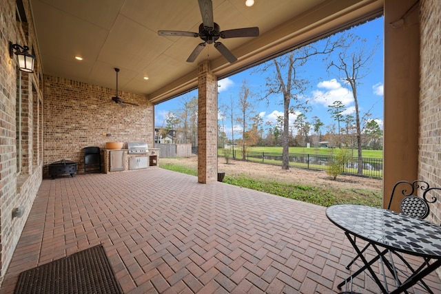 view of patio / terrace with exterior kitchen, grilling area, a water view, and ceiling fan